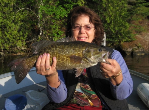 Lovely photo of a fisher woman holding her nice catch! Looks like a beautiful day.